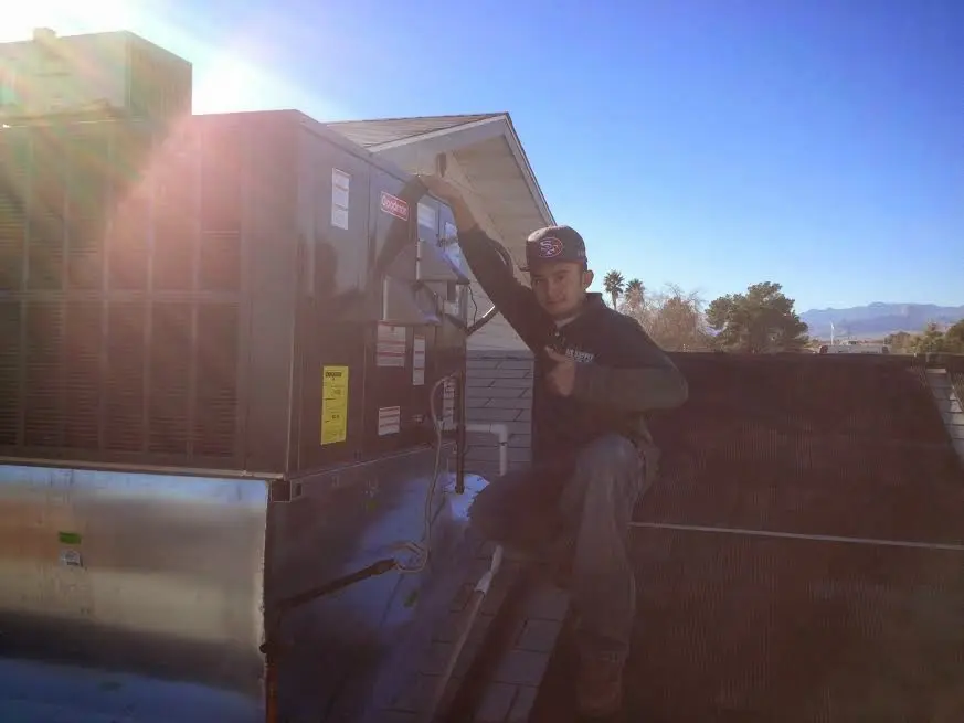 HVAC technician performing Air Duct Cleaning on a rooftop unit in Washington